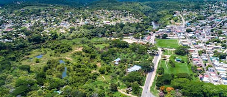 An aerial view of a town with a main road, green spaces, and buildings.