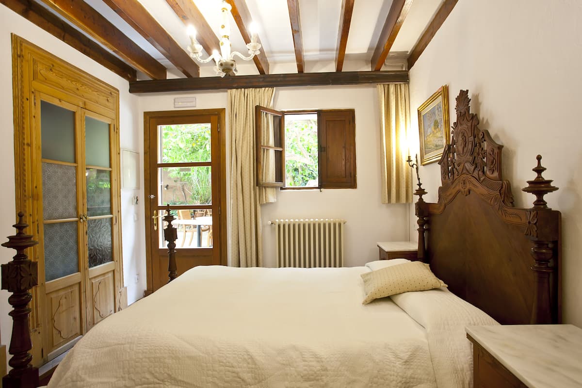 A bedroom with a large bed, wooden headboard, and a window with curtains.