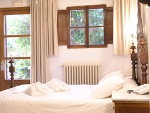 Una cama bien hecha con sábanas y toallas blancas, un cabecero de madera y una ventana con cortinas.