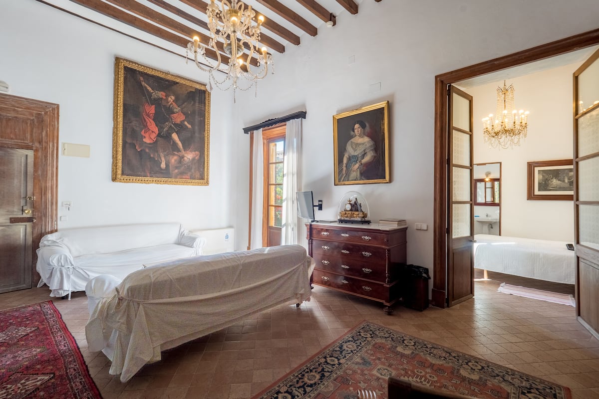 A bedroom with a bed, dresser, and two paintings.