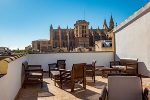 A rooftop terrace with wooden furniture and a view of a historic building with Gothic architecture. - Dalt Murada Turismo de Interior (Palma de Mallorca)