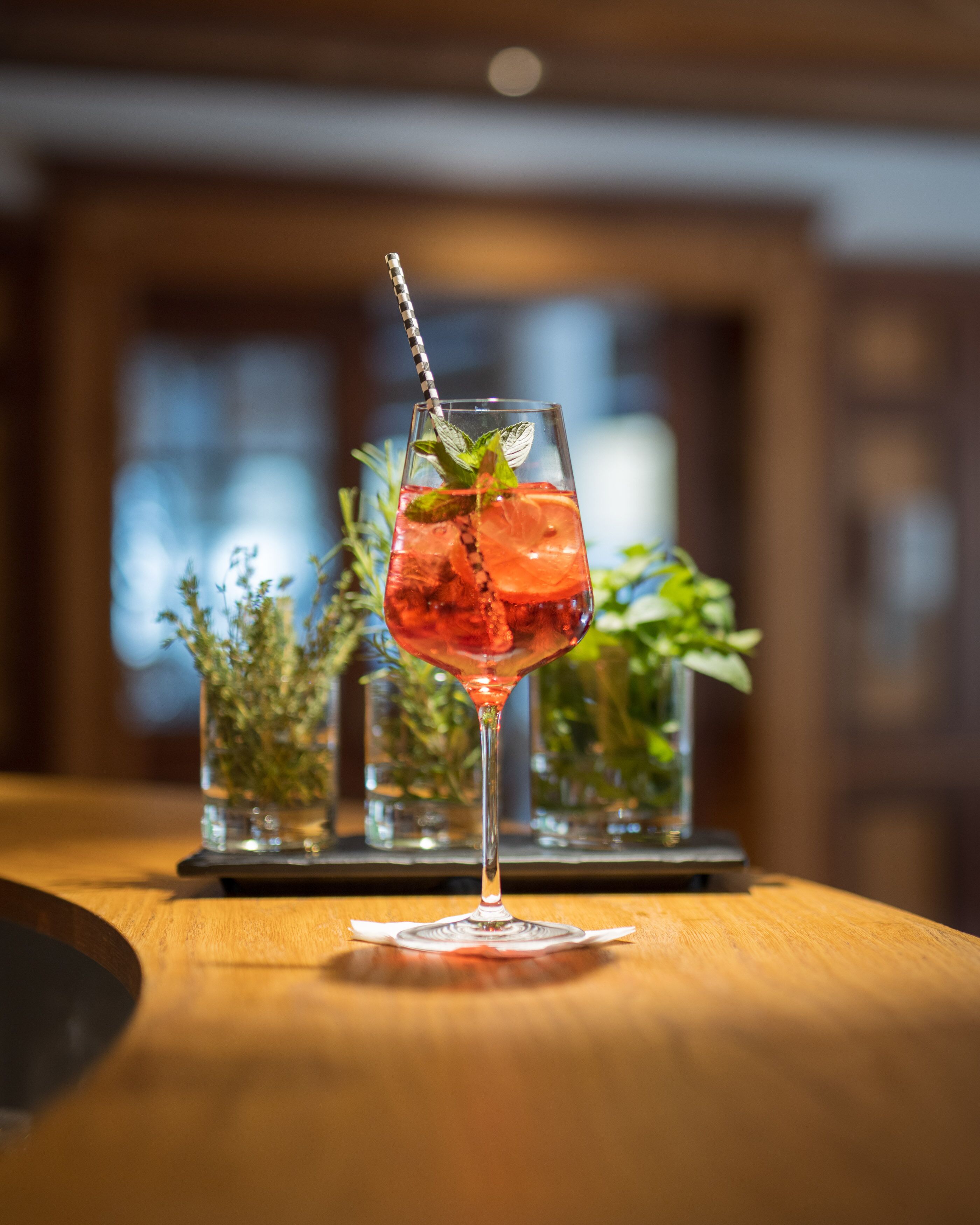 A cocktail glass with a striped straw on a wooden table.