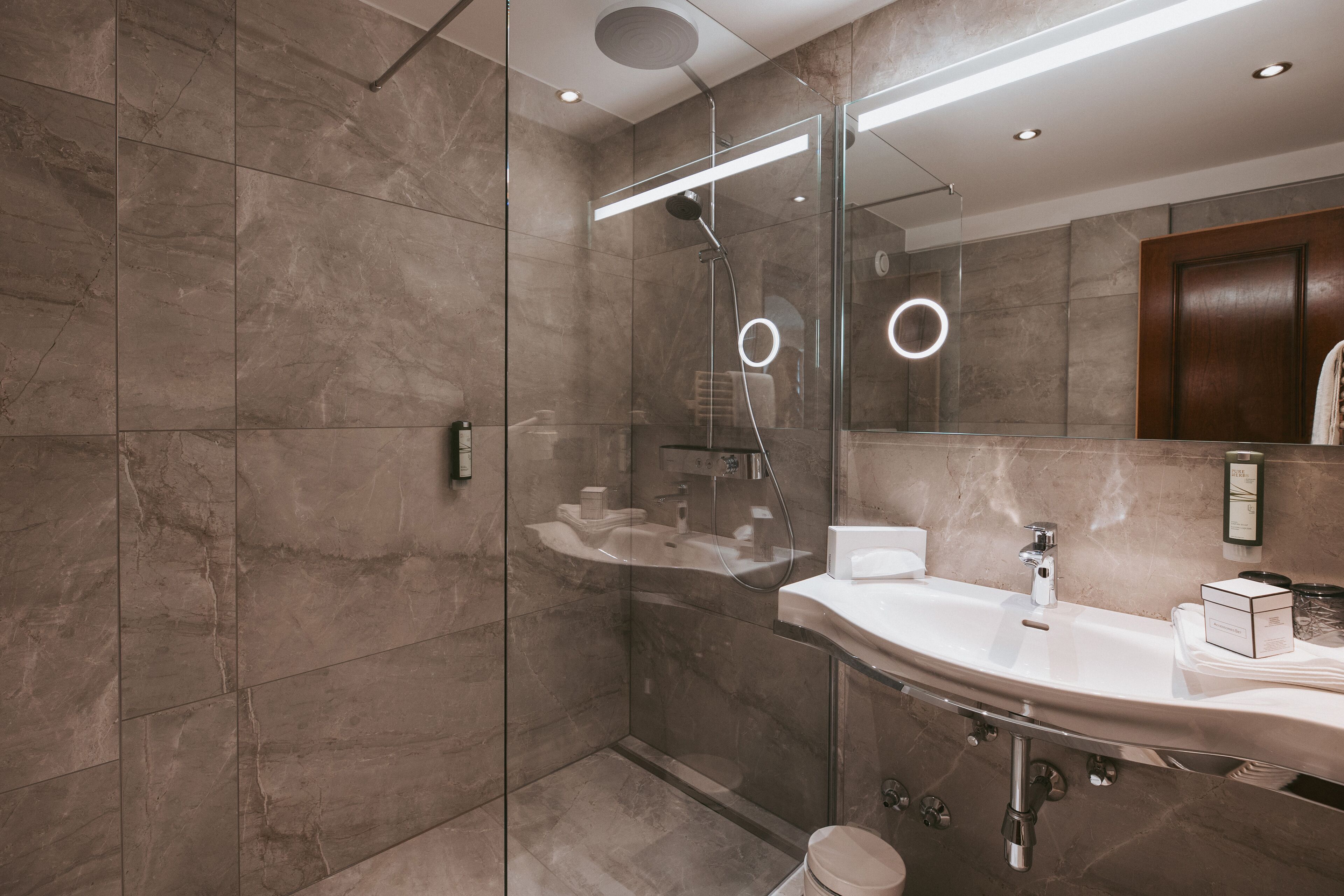 A modern bathroom with a glass-enclosed shower, a vanity with a sink, and a mirror.