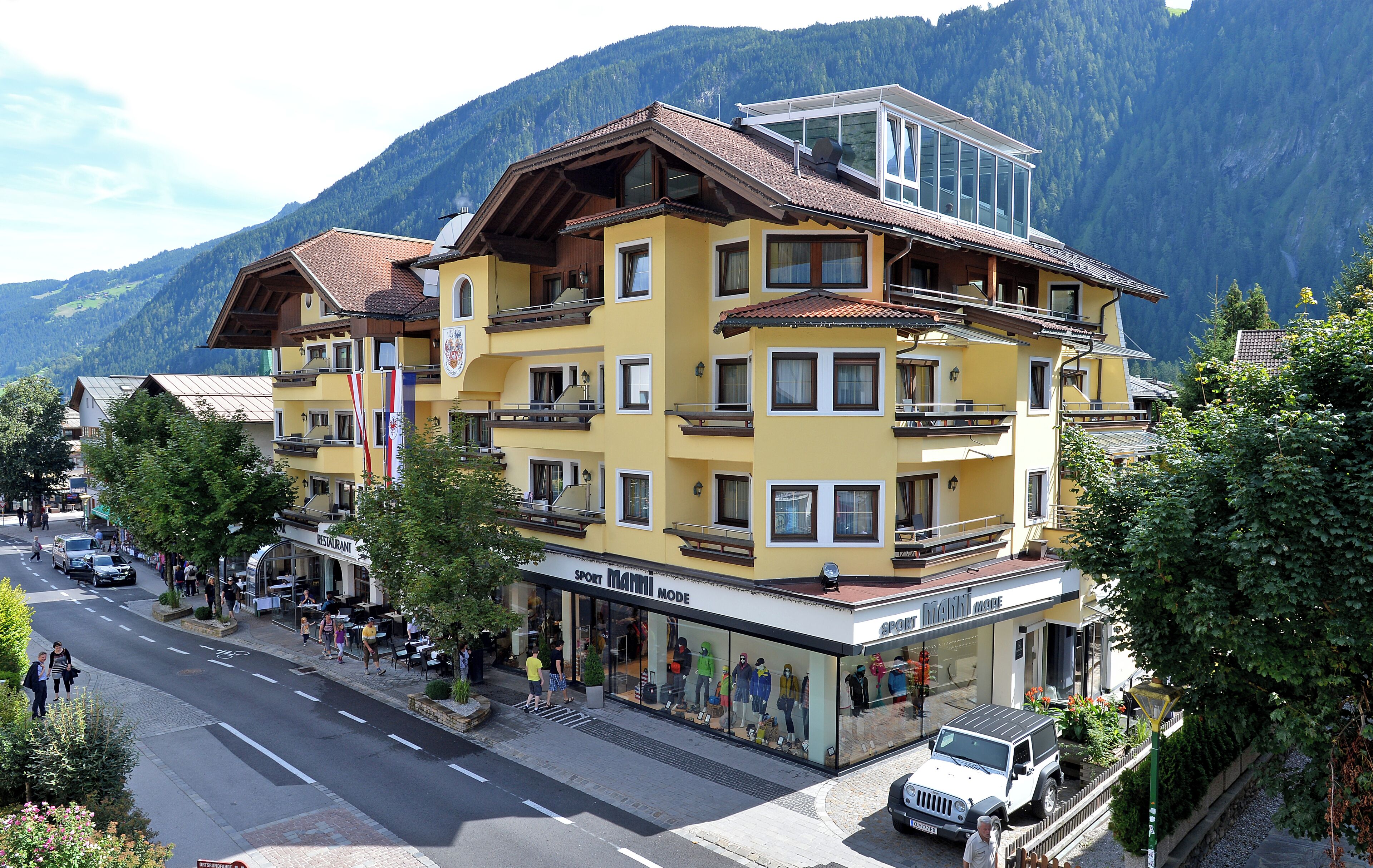 A multi-story building with balconies, a restaurant, and a shop named "Sport Mann".