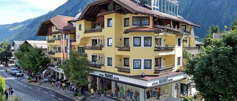 A multi-story building with balconies, a restaurant, and a shop named "Sport Mann".