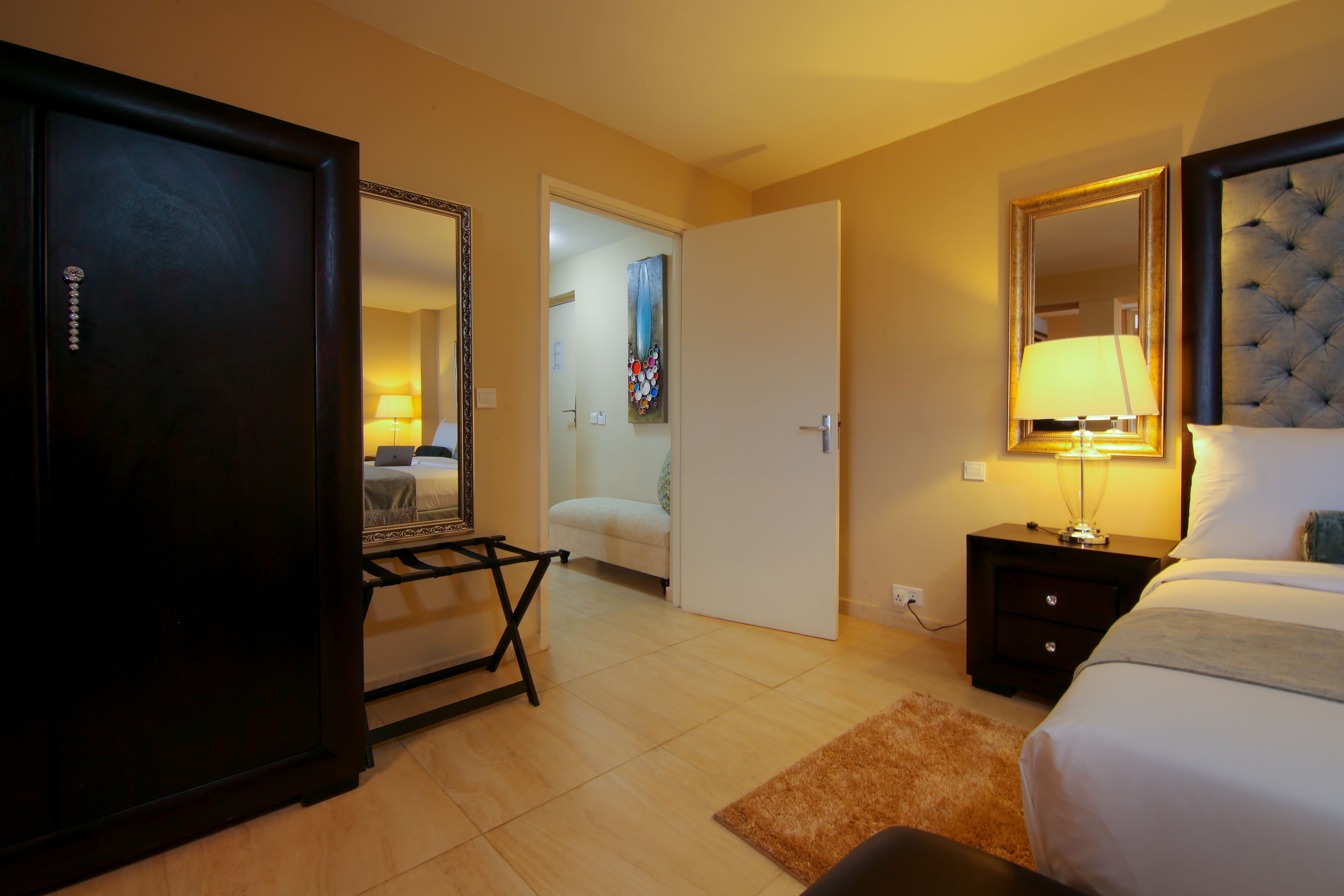 A hotel room with a bed, bedside table, lamp, and a wardrobe.