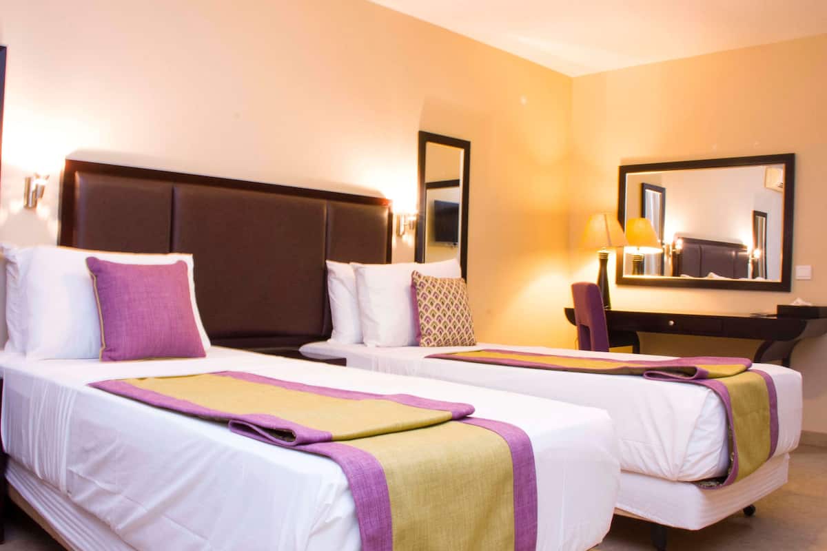 A hotel room with two beds, a desk, and a chair.