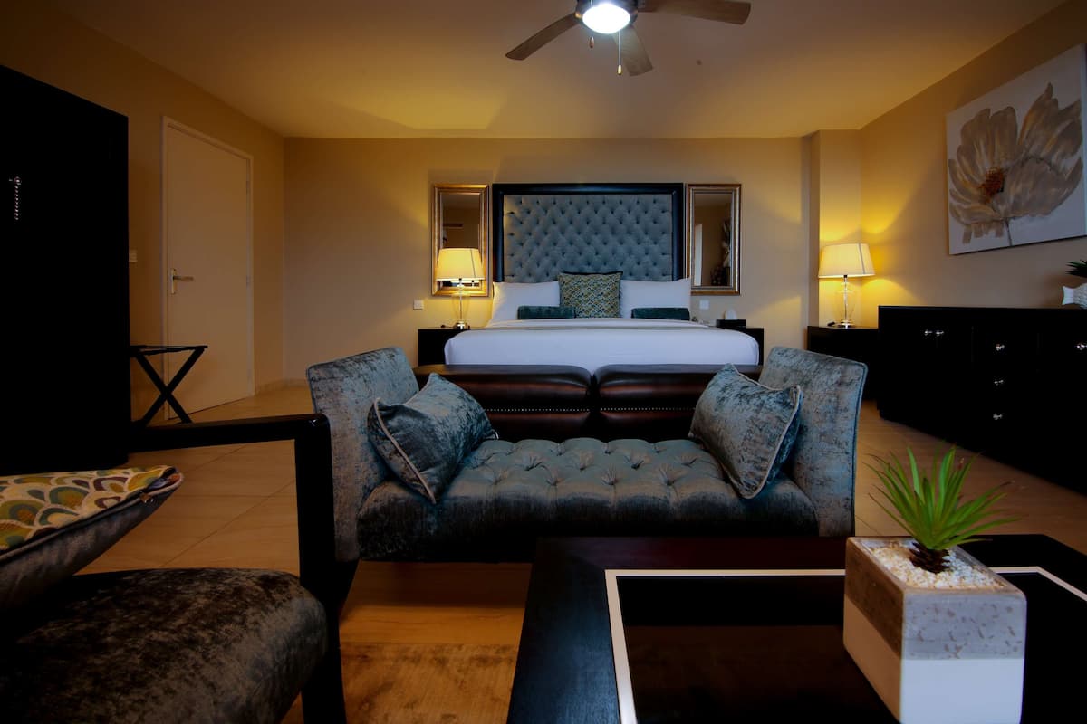 A hotel room with a large bed, a sofa, a coffee table, and a TV.