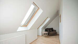 A room with sloped ceilings, a radiator, a wooden floor, a small table, and a sofa. - Hotel Laxnes (Mosfellsbær)
