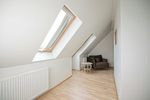 A room with sloped ceilings, a radiator, a wooden floor, a small table, and a sofa. - Hotel Laxnes (Mosfellsbær)