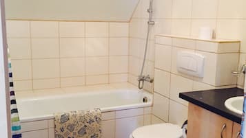 Et badeværelse med badekar, toilet og håndvask.