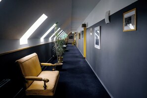A hallway with a chair, potted plants, and framed pictures on the walls. - Hotel Laxnes (Mosfellsbær)