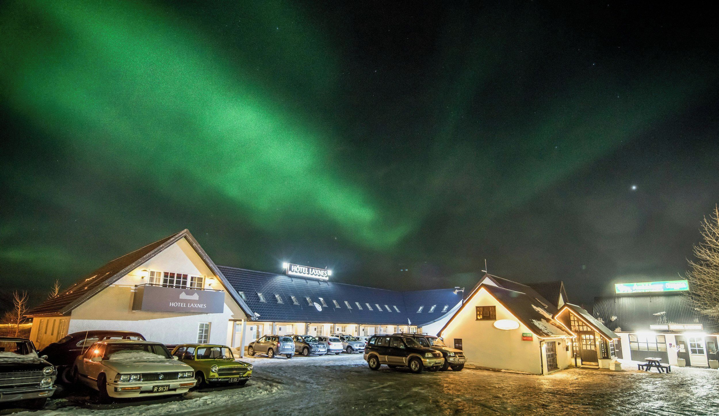 Ein Hotel mit der Aufschrift 'HOTEL LAXNES' unter einem Nachthimmel mit Polarlichtern.