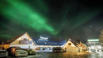 A hotel with a sign 'HOTEL LAXNES' under a night sky with aurora borealis.