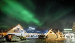 A hotel with a sign 'HOTEL LAXNES' under a night sky with aurora borealis.