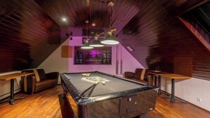 A billiards room with a pool table, leather seating, and pendant lighting. - Hotel Laxnes (Mosfellsbær)