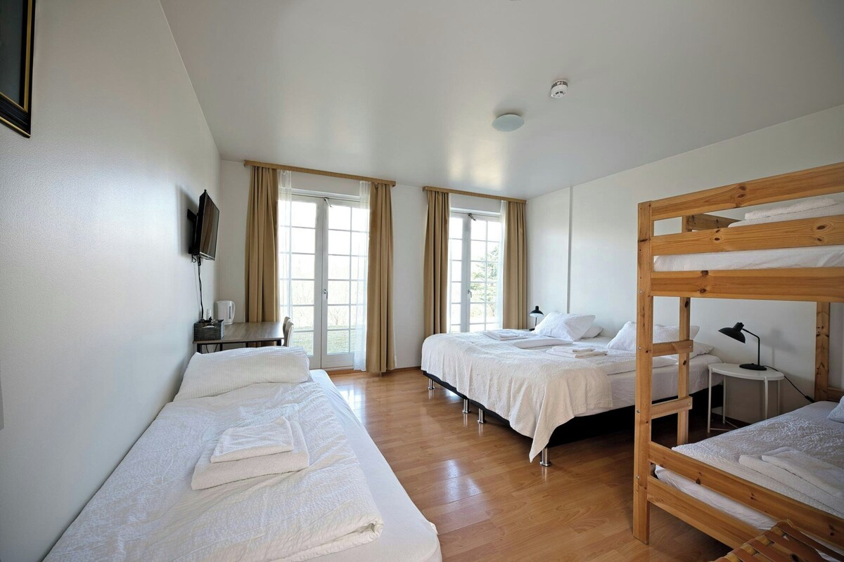 A room with two beds, a desk, a chair, and a television.