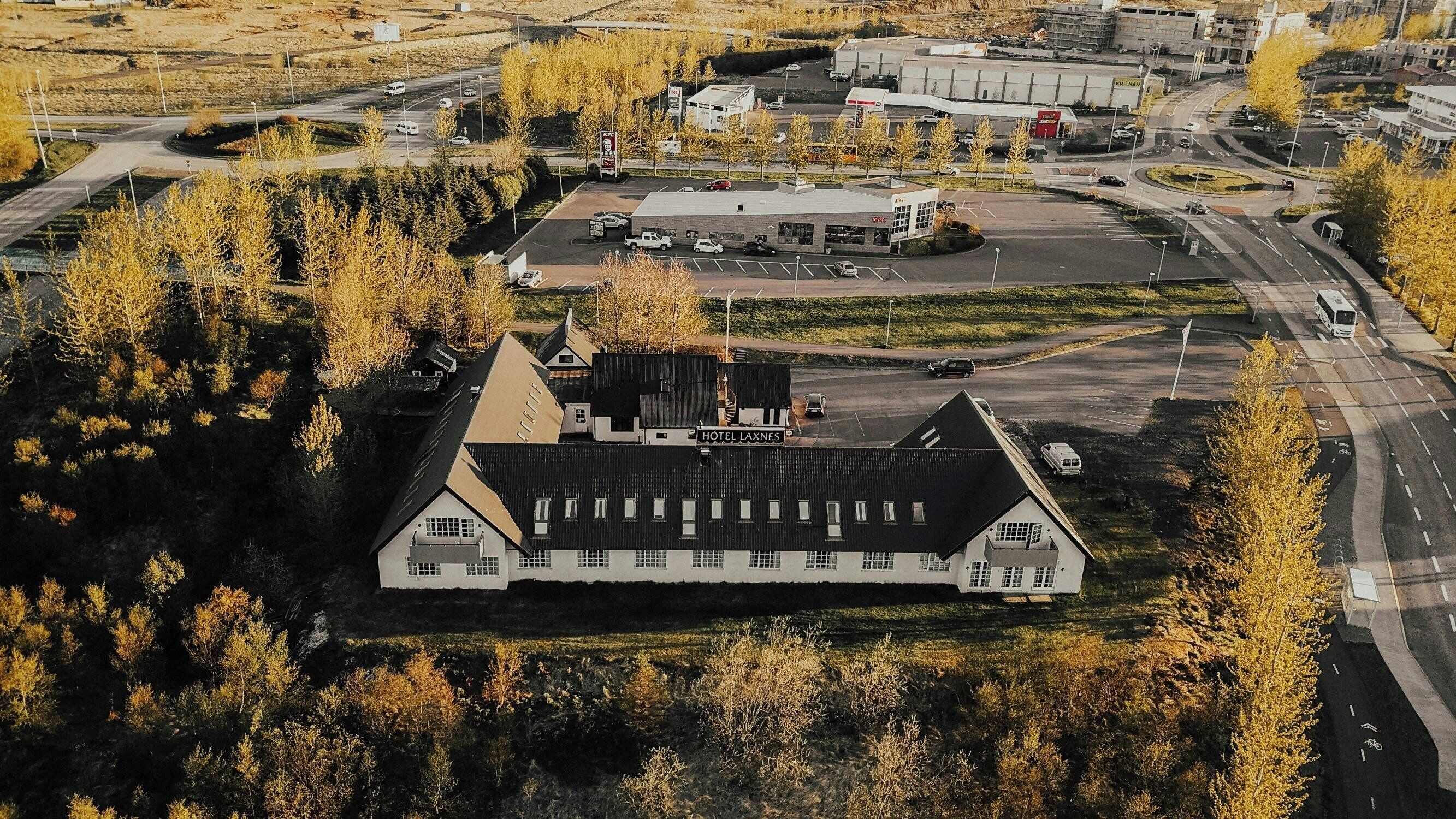 A large, two-story building with a flat roof, surrounded by trees and a parking lot.