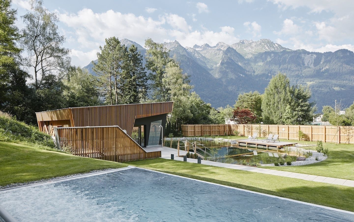 Ein moderner Poolbereich im Freien mit Holzterrasse, kleinem Pool und Bergblick.