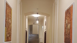 A hallway with a carpet, a staircase, and wall-mounted artwork. - Appartements Hermine (Vienna)