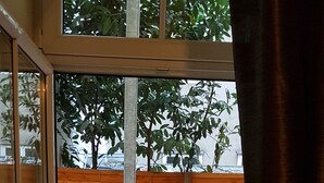 A view through a glass door into a patio area with a wooden table, a potted plant, and a brick wall. - Appartements Hermine (Vienna)