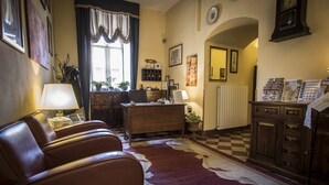 A cozy living room with leather chairs, a desk, and a checkered rug. - Palazzo Fani Mignanelli (Siena)