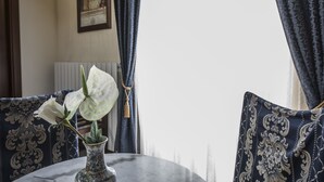 A table with a vase of white flowers, blue patterned cushions, and a framed picture on the wall. - Palazzo Fani Mignanelli (Siena)