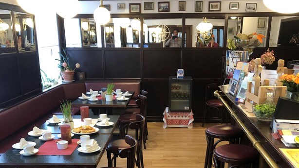 A restaurant with wooden flooring, multiple tables and chairs, and hanging pendant lights. - Brocki's Hotel Stadt Hamburg (Parchim)