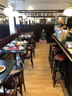 Ein Restaurant mit Holzboden, mehreren Tischen und Stühlen sowie hängenden Pendelleuchten.