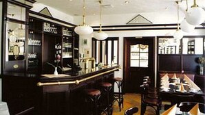 A bar area with stools, a counter, and hanging light fixtures. - Brocki's Hotel Stadt Hamburg (Parchim)