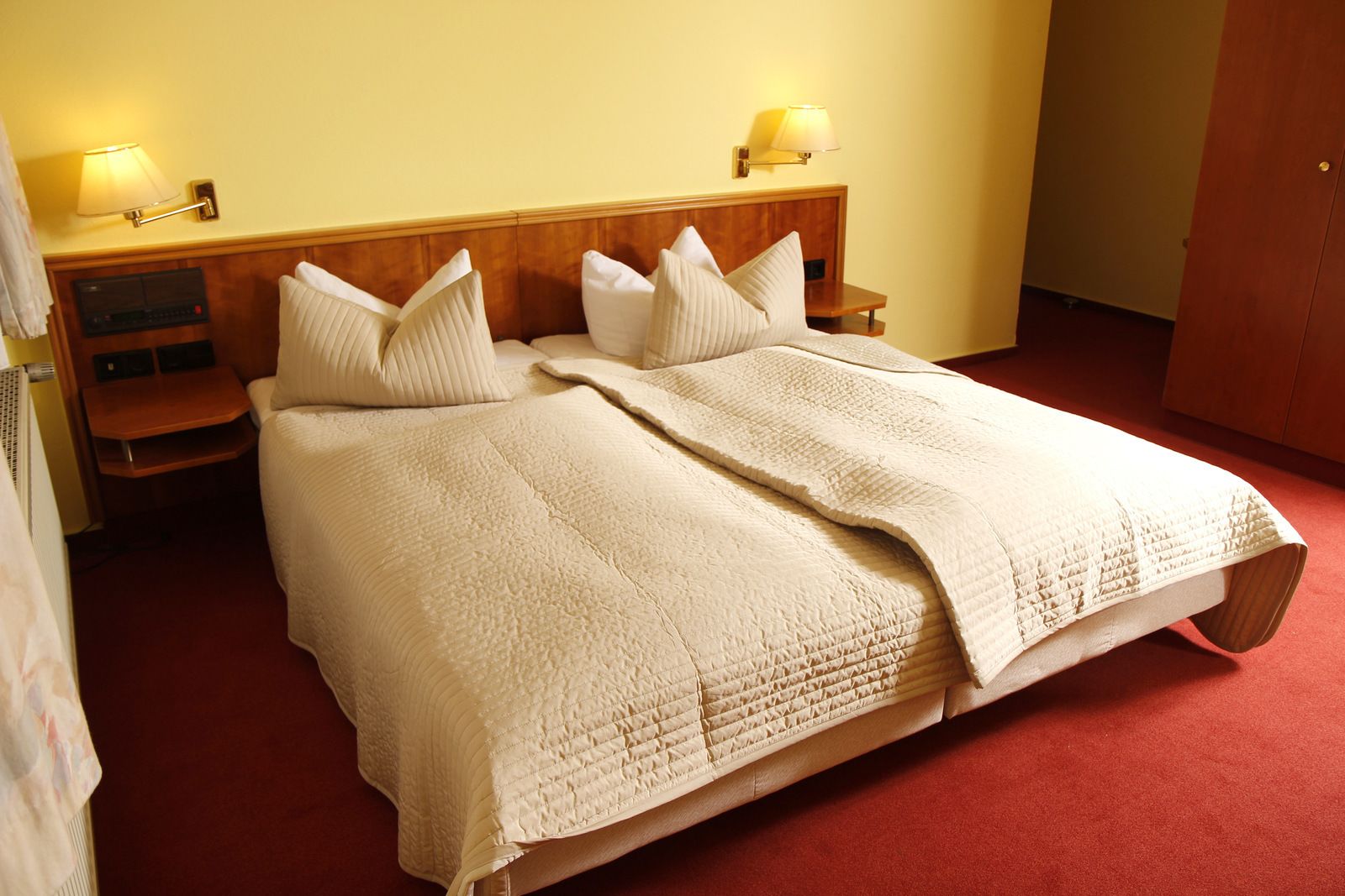 A double bed with a quilted blanket, two bedside tables with lamps, and a wooden headboard.