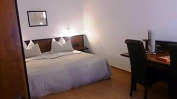 A hotel room with a bed, a desk, and a chair.