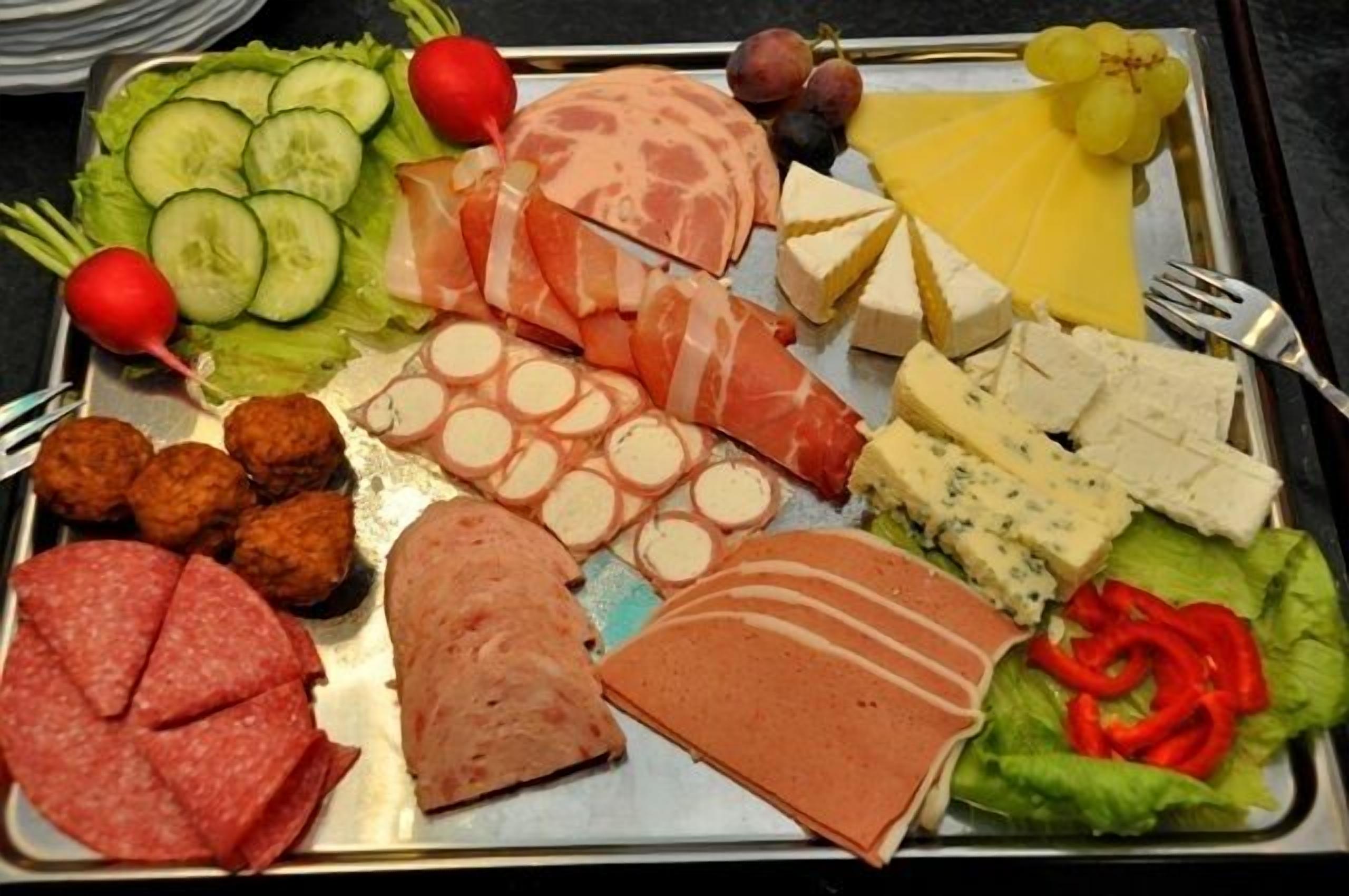 A variety of meats and cheeses on a tray.