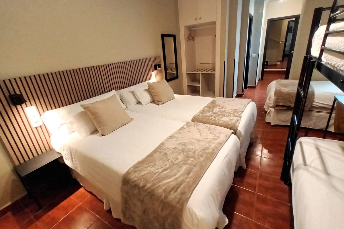 A hotel room with a large bed, a bedside table, a wardrobe, and a mirror.