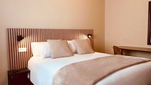 Una cama bien hecha con cabecera de madera, una mesita de noche y una lámpara de pared.