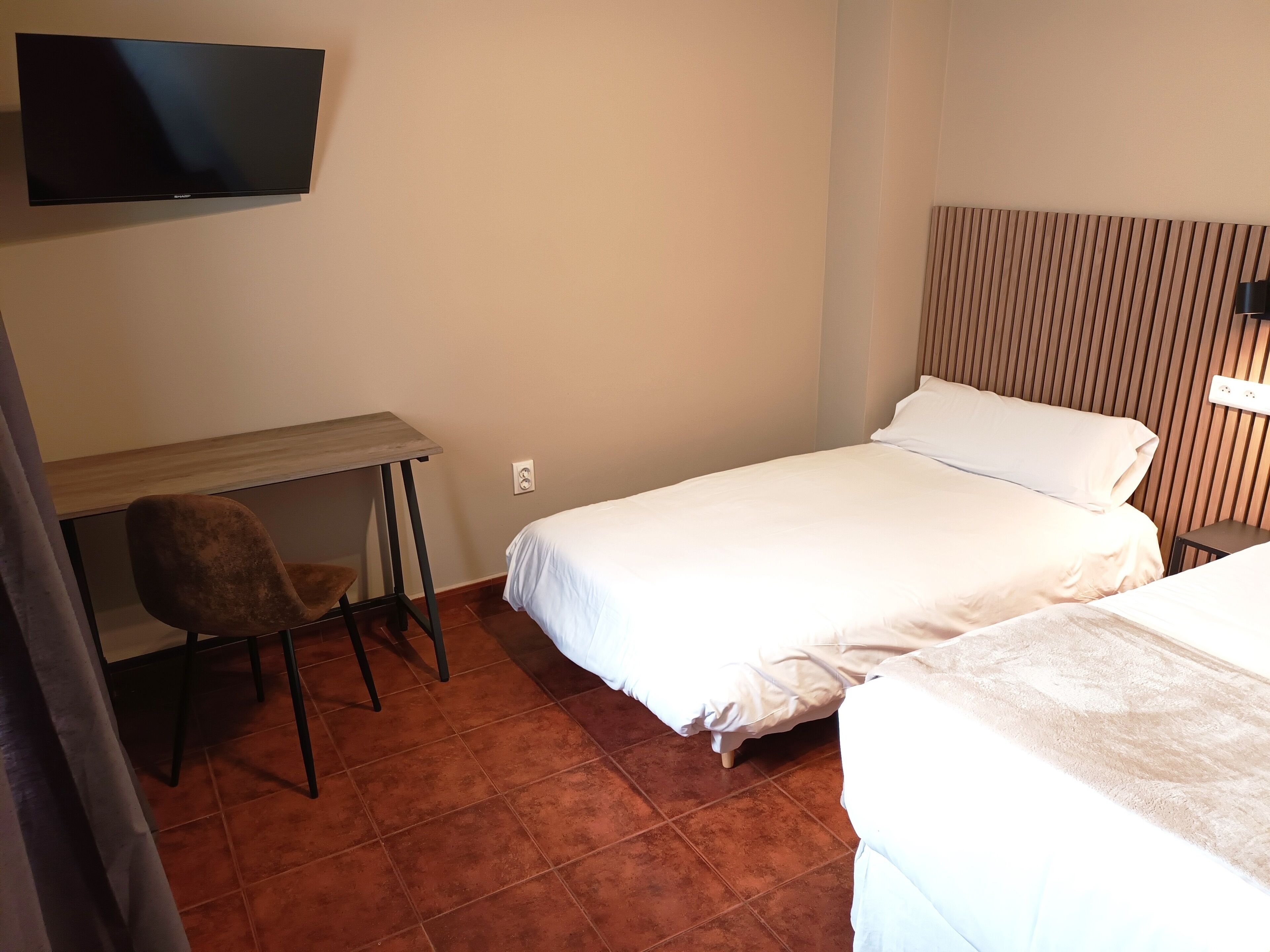 A hotel room with a bed, a desk, a chair, a television, and a nightstand.