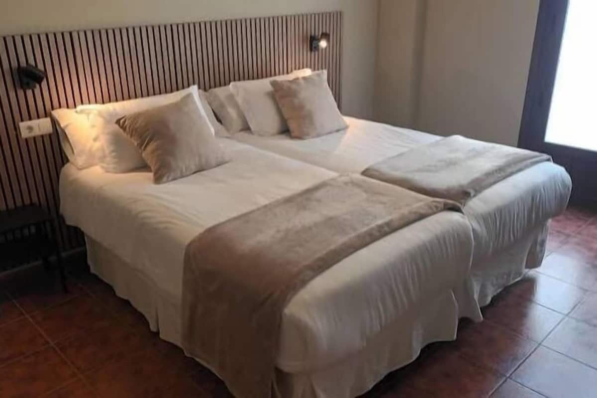 A double bed with a striped headboard, a bedside table, and a window with natural light.