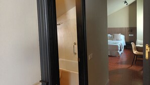 Una habitación de hotel con una bañera, una cama y una silla.