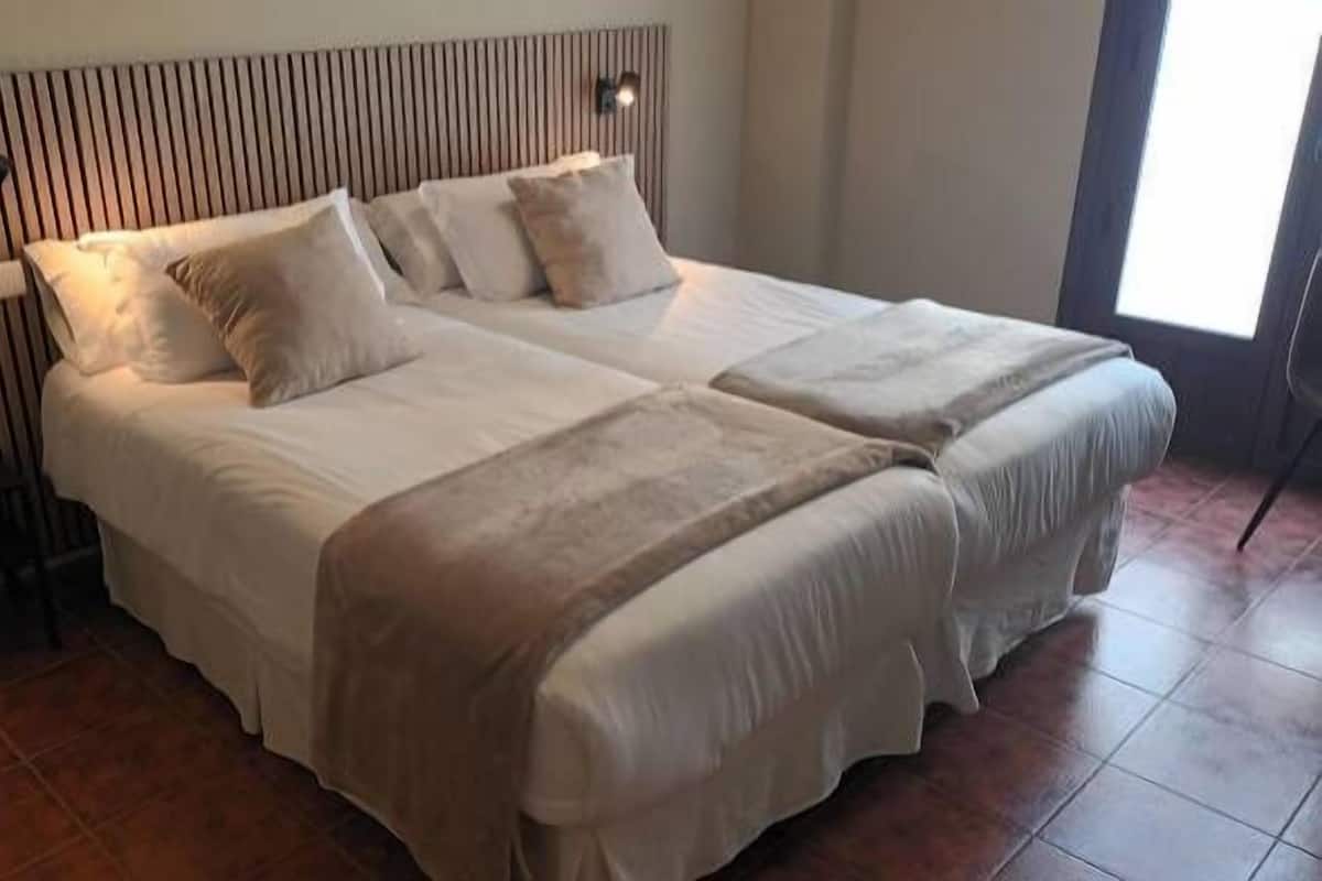 A double bed with a wooden headboard, two pillows, and a bedside table.