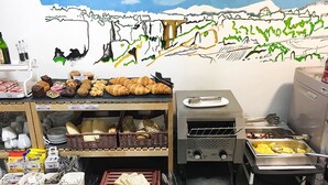 Montaje de bufé con diferentes opciones de comida, incluyendo pastelería y pan, además de una estación de parrilla.