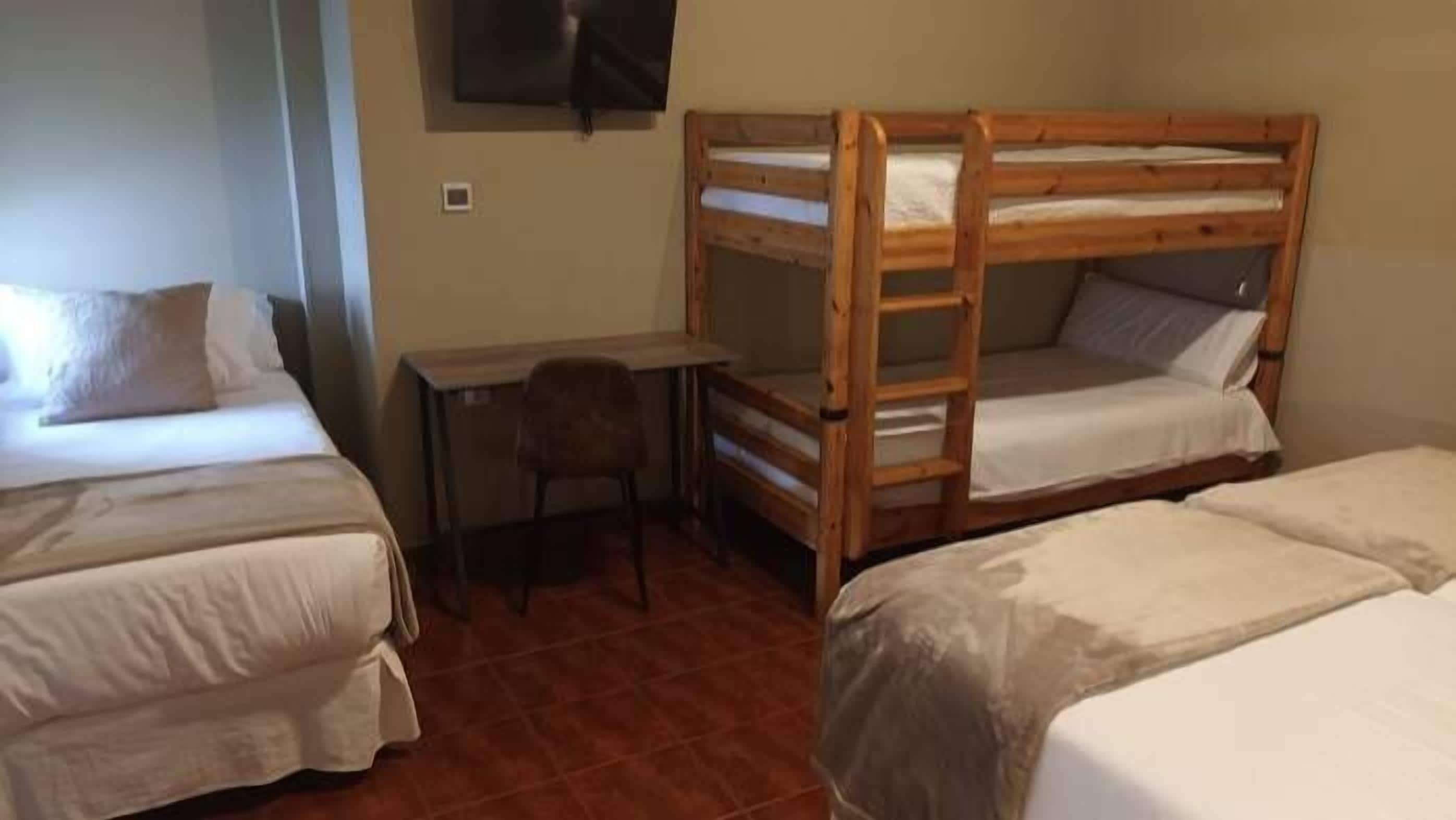 Un dormitorio con literas, un escritorio y una silla.