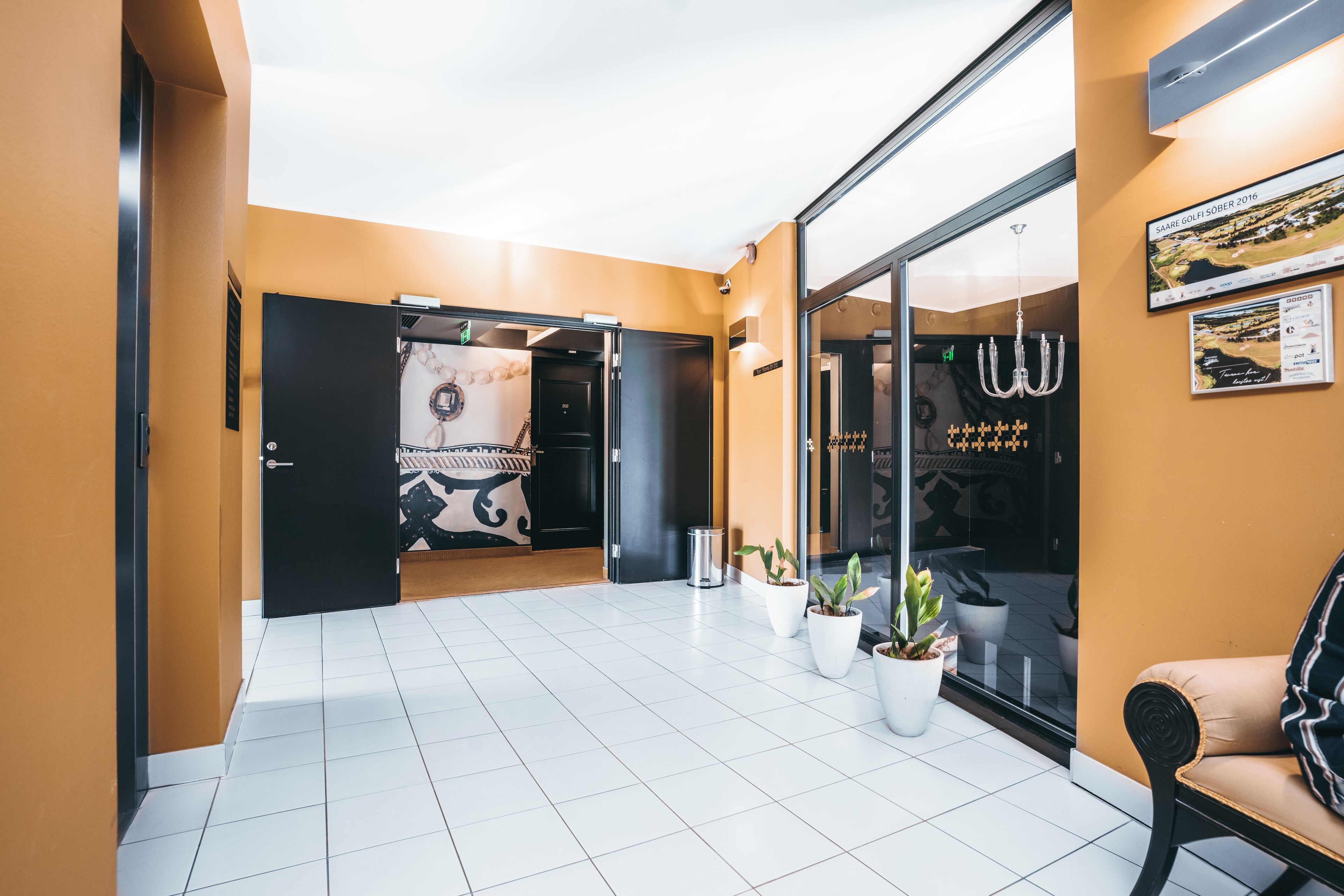 Un vestíbulo de hotel con diseño moderno, que presenta un mostrador de recepción, una zona de estar con sofá y plantas en macetas.