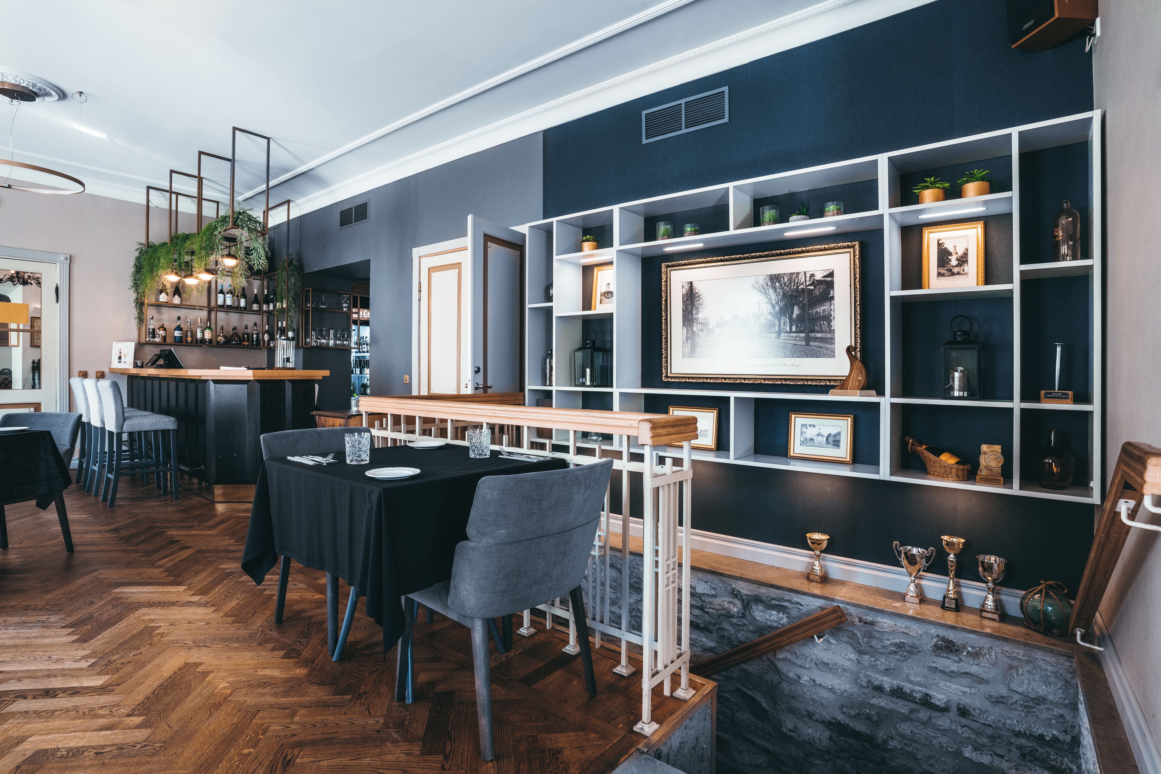 A dining area with a long table, chairs, and a bar with shelves.