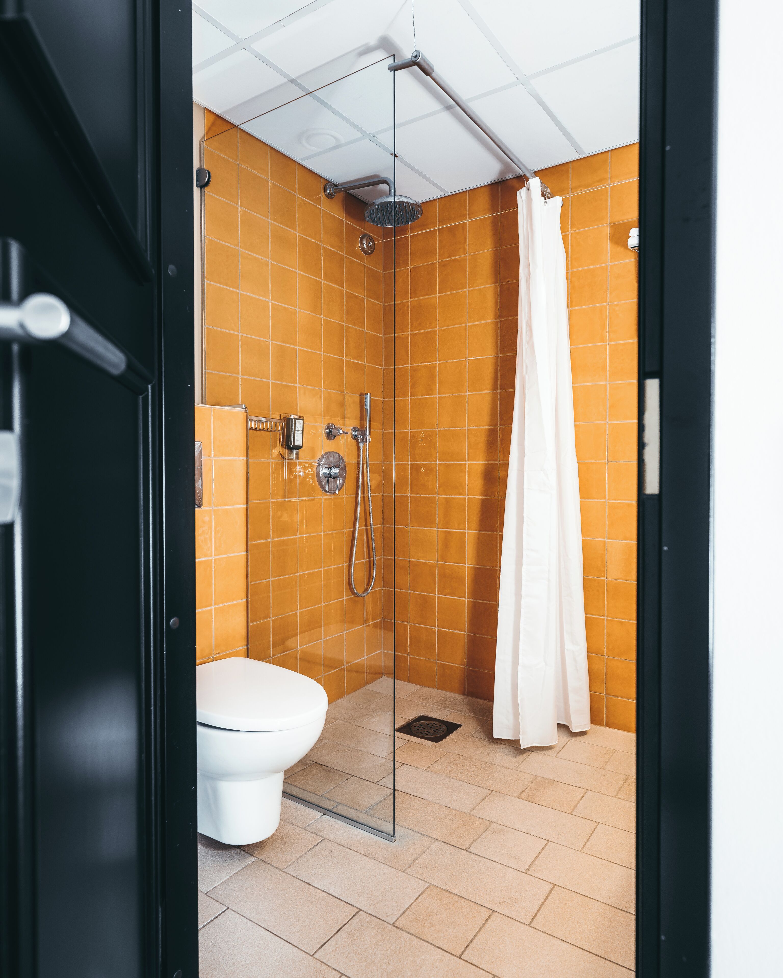 Un baño pequeño con ducha, inodoro y mampara de vidrio.