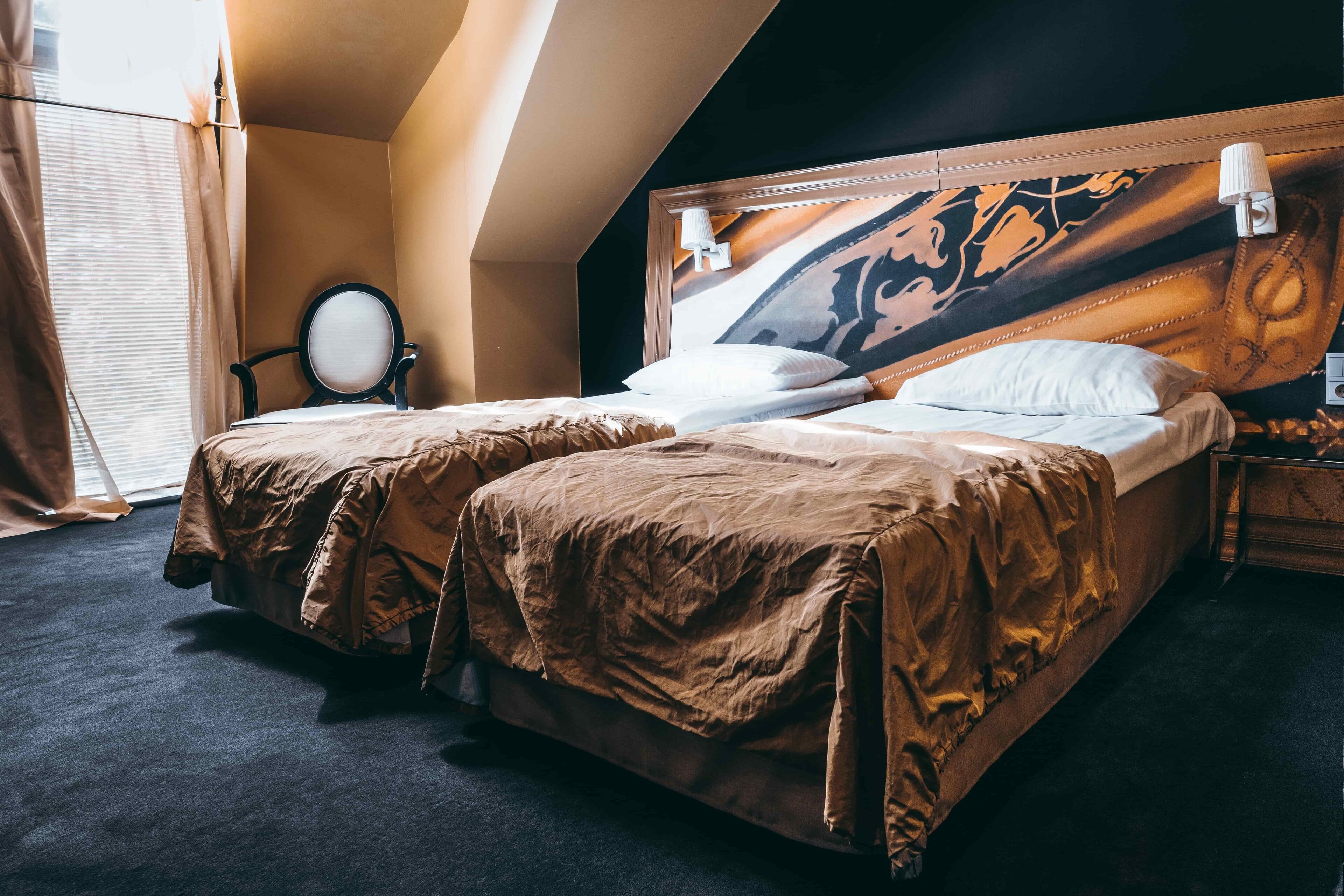 Una habitación de hotel con dos camas, un espejo grande y un cabecero con un panel decorativo.