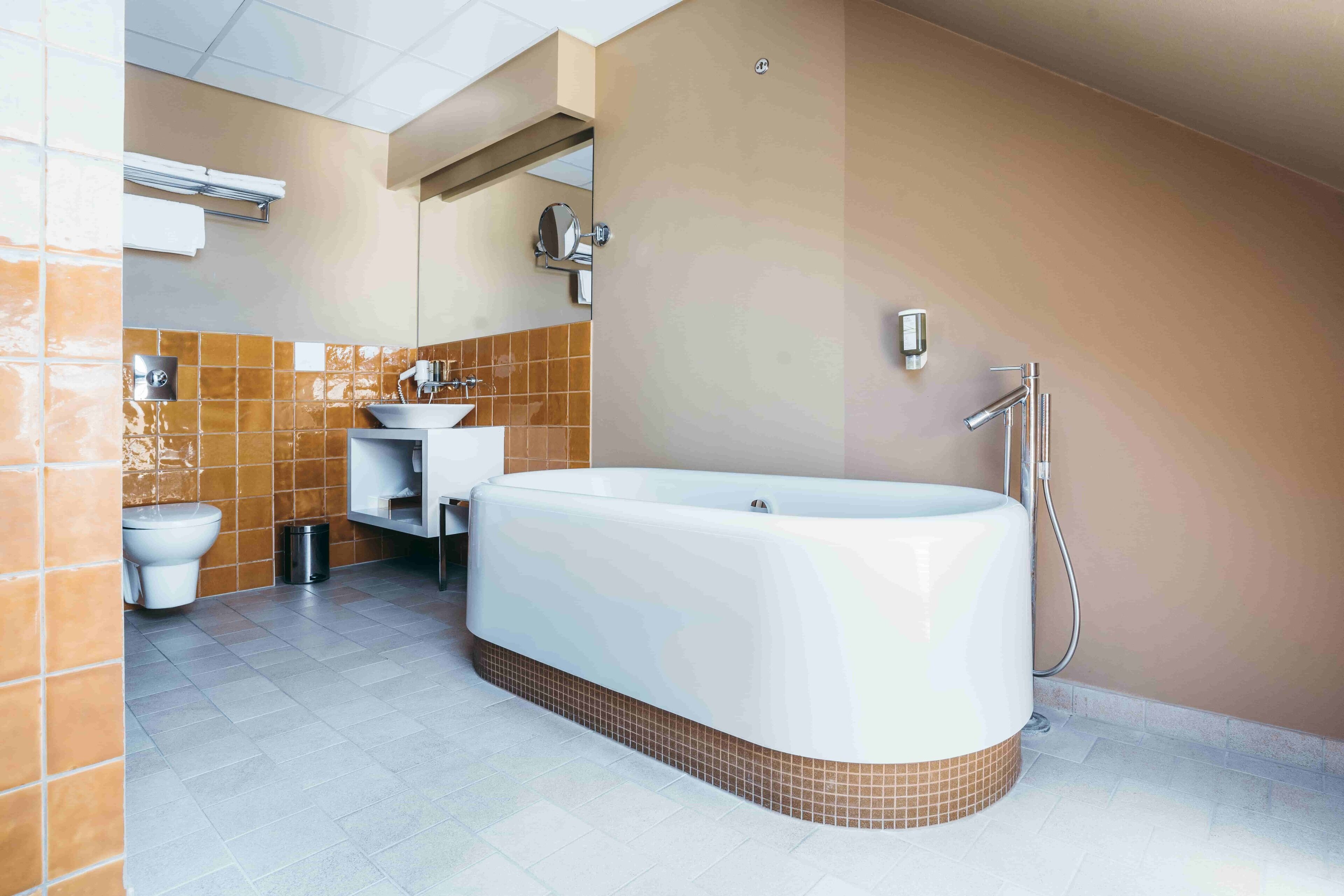 Un baño moderno con una bañera grande, un inodoro y un lavamanos.
