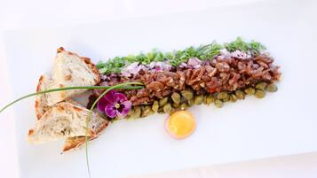 A dish with bread, a flower, and a lemon slice on a white plate.