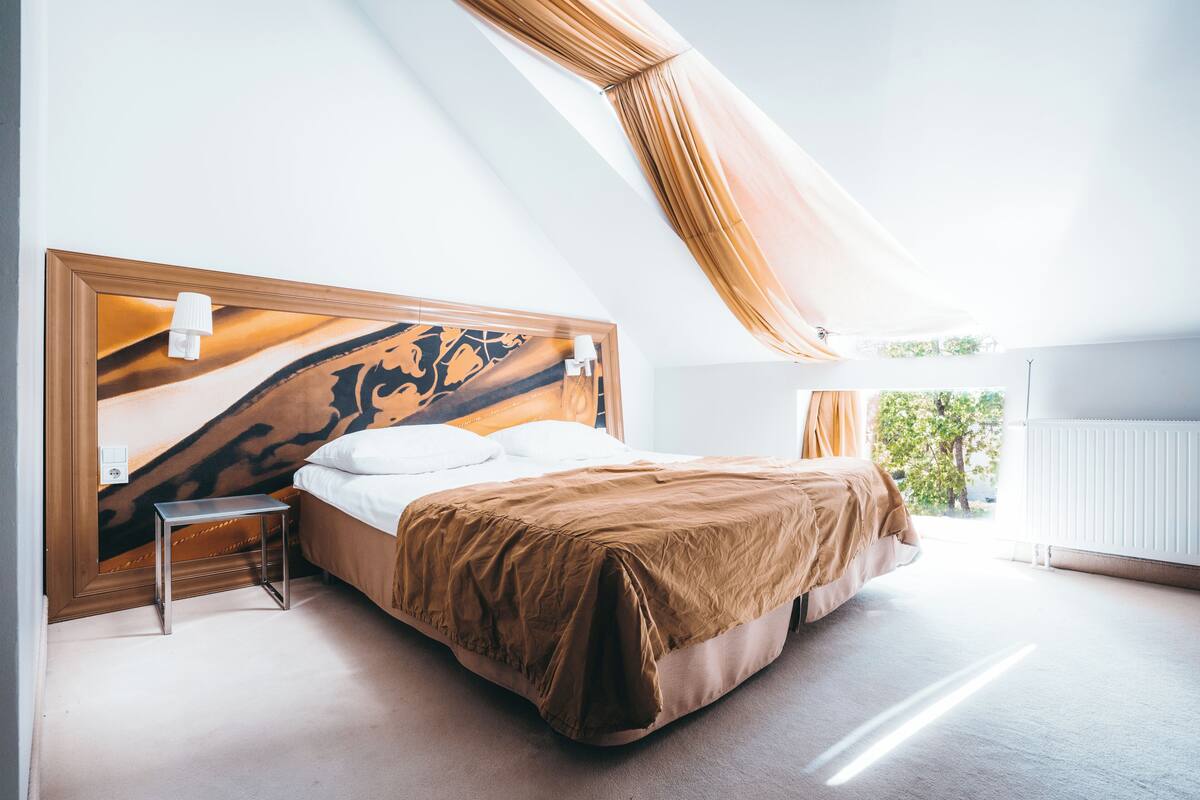 A bedroom with a large bed, a small table, and a unique headboard design.