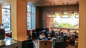 Un espace intérieur accueillant avec des fauteuils et des tables confortables, une grande fresque murale et des lampes suspendues.