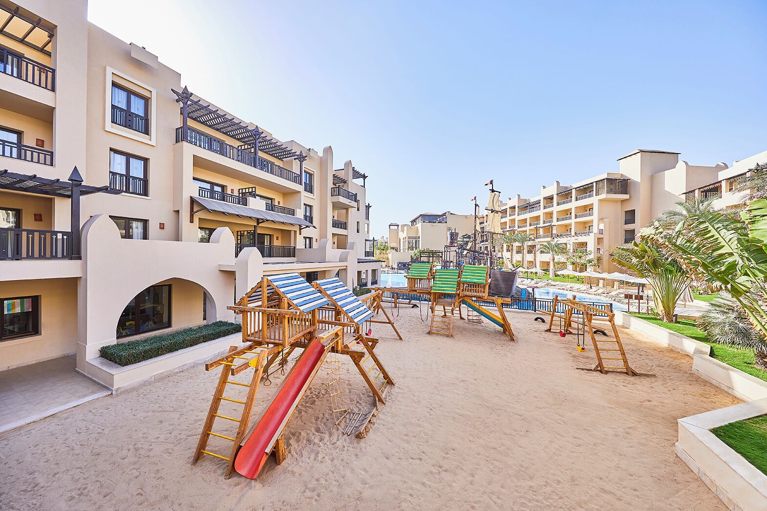 Ein Resort mit mehreren Gebäuden, einem Poolbereich und Liegestühlen.